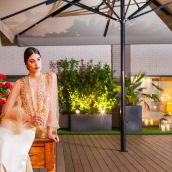 Novia apoyada en una mesa, sosteniendo una copa en la terraza de Mestura Restaurante